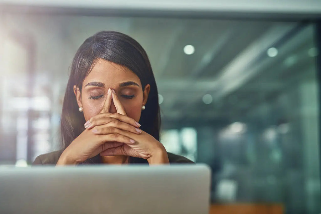 Woman avoiding common trade show mistakes at laptop by office window