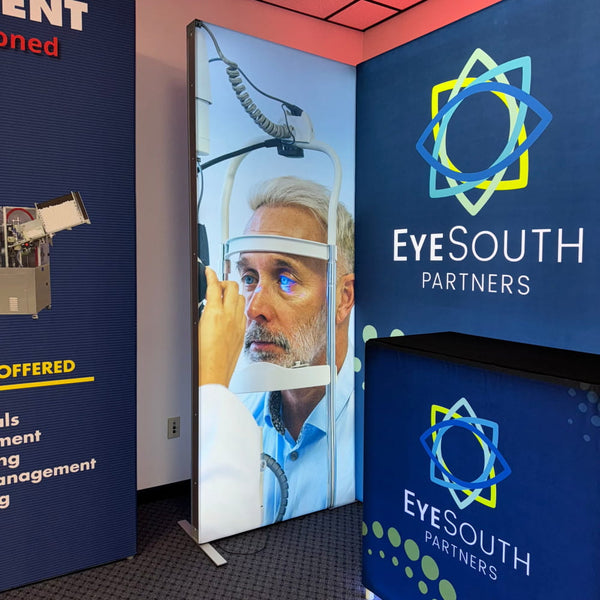 Blue and yellow Eyesouth Partners logo on dark blue backdrop in 3ft Frameless SEG Lightbox Display