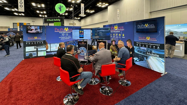 Men at ProPhoenix booth on red stools with monitors in 4.5ft SEG lightbox