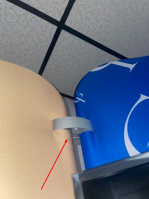 Gray plastic clip securing blue and white branded display to beige surface with 50mm aluminum butterfly clamp