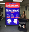 Blue inflatable banner with cartoon house and building characters promoting Envestor on 5ft backlit tension fabric display