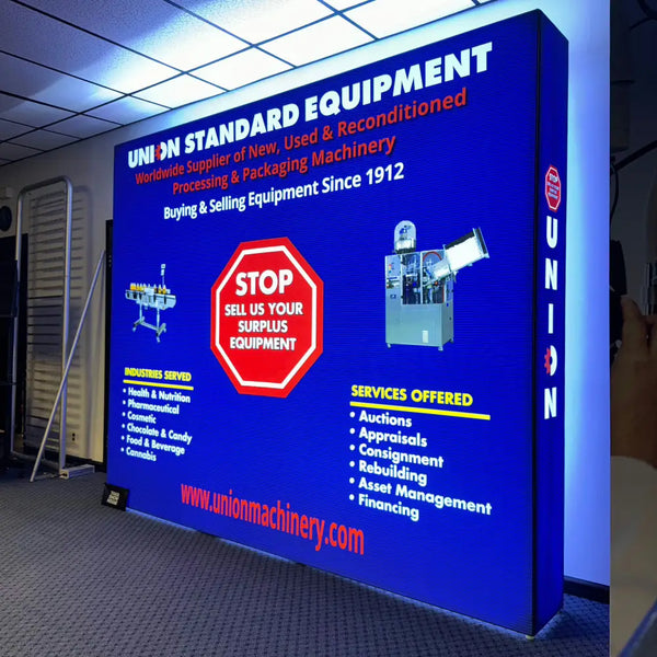 Blue illuminated trade show banner for Union Standard Equipment machinery services in 8ft Backlit SEG Light Box Wall