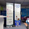 Blue and white vertical banner advertising dental pay-per-call program on Classic 24 Inch Retractable Banner Stand