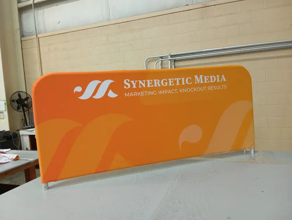 Orange fabric banner with Synergetic Media logo for crowd control barrier