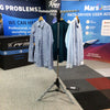 Silver tripod clothes drying rack with circular top and hooks holding shirts