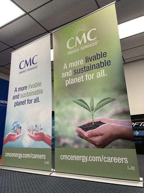 Green and white CMC Energy Services retractable banner with hand holding soil and young plant