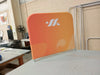 Orange promotional banner with white logo and wave design on small half wall barrier display