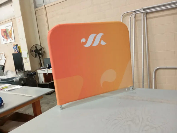 Orange promotional banner with white logo and wave design on small half wall barrier display