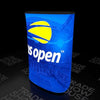 Blue-lit display stand with yellow white US Open logo on Triangle Backlit Inflatable Counter