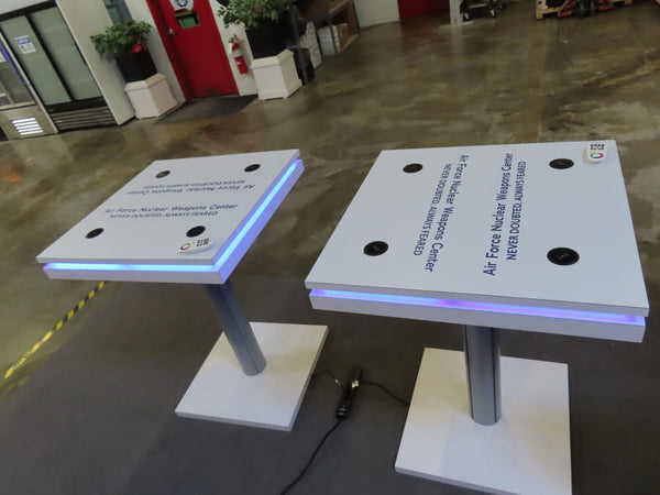 White interactive tables with blue LED edges and black sensors for wireless charging kit