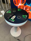 Black circular table with white base, blue LED ring, AgroLiquid logos, speakers