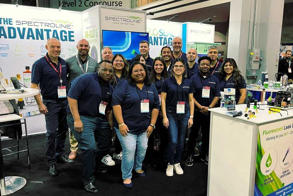 Group in navy polo shirts at Spectroline trade show booth for event planning
