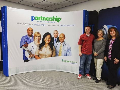 Blue and white curved banner with Partnership Health Center logo and smiling healthcare professionals