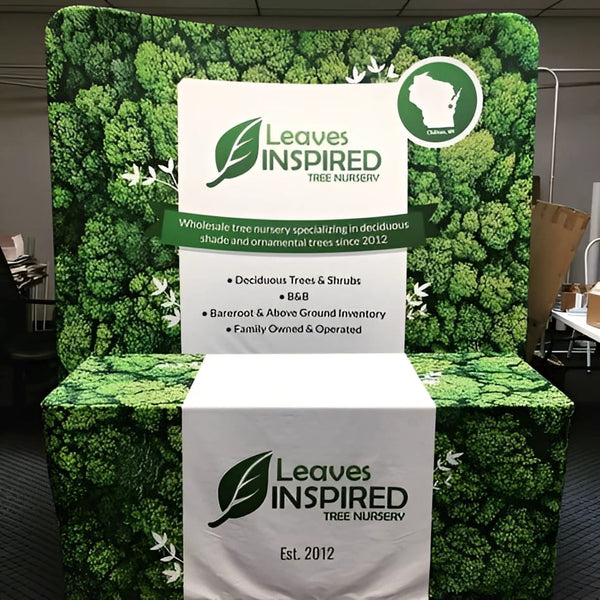 8ft Curved Tension Fabric Display with green leaf-patterned stand and Leaves Inspired Tree Nursery logo