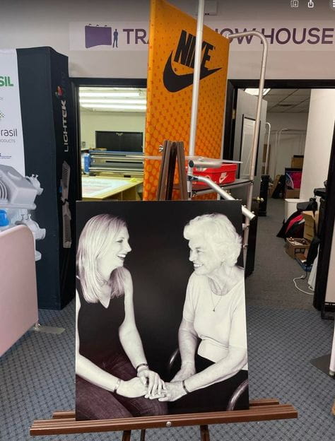 Black-and-white portrait of two women holding hands on wooden easel