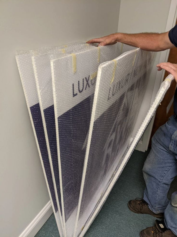 Stack of four framed luxury art panels in bubble wrap