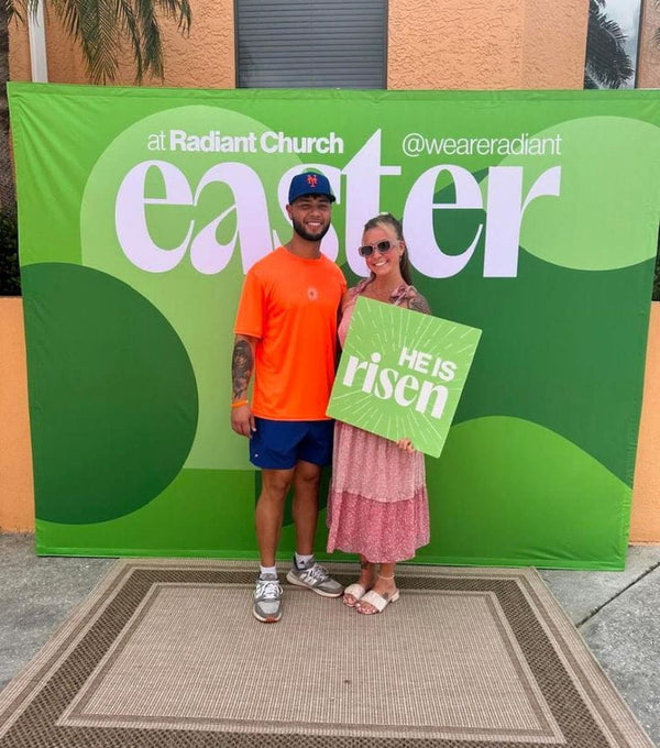 Green He Is Risen mounted poster sign with white text and sunburst