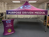 Purple pop-up tent with Purpose Driven Media branding on EZ Breezy Media logo podium