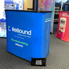 Blue rebound trade show display box with white and green branding