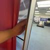 Hand holding red curtain edge for frameless lightbox wing nut display